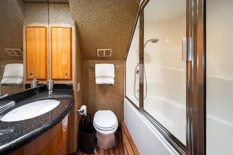 Slide: The Image of Luxurious bathroom with granite sink, wooden cabinets, and a shower in a Hatteras 64 Motor Yacht. - 21