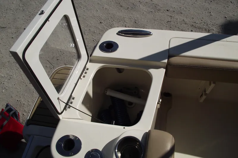 Slide: The Image of 2022 Scout 215 Dorado boat storage compartment with open lid and cup holders. - 32