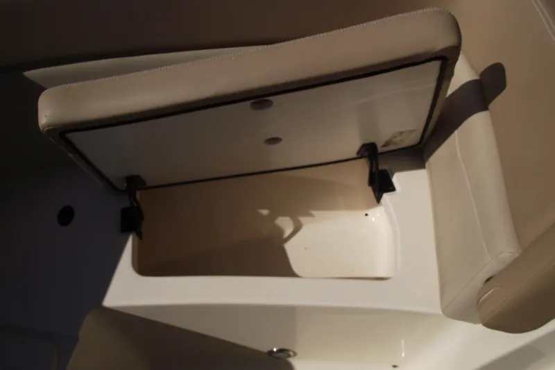 Slide: The Image of 2022 Scout 215 Dorado boat storage compartment with open lid and beige interior. - 9