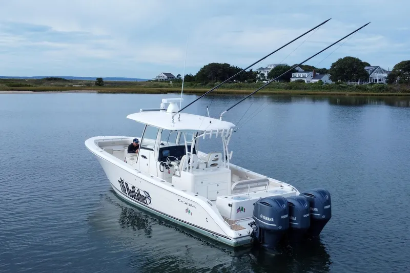 Slide: The Image of 2015 Cobia 344 Center Console boat with triple Yamaha engines on calm water. - 11