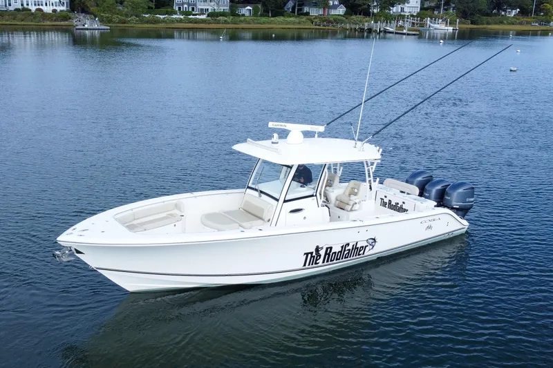 Slide: The Image of 2015 Cobia 344 Center Console boat on calm water, featuring triple outboard engines. - 13