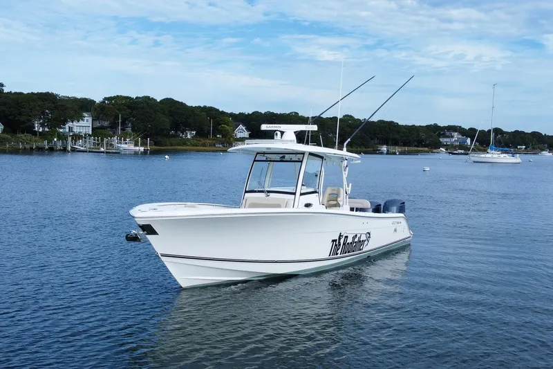 Slide: The Image of 2015 Cobia 344 Center Console boat on calm water, with fishing rods and scenic background. - 2