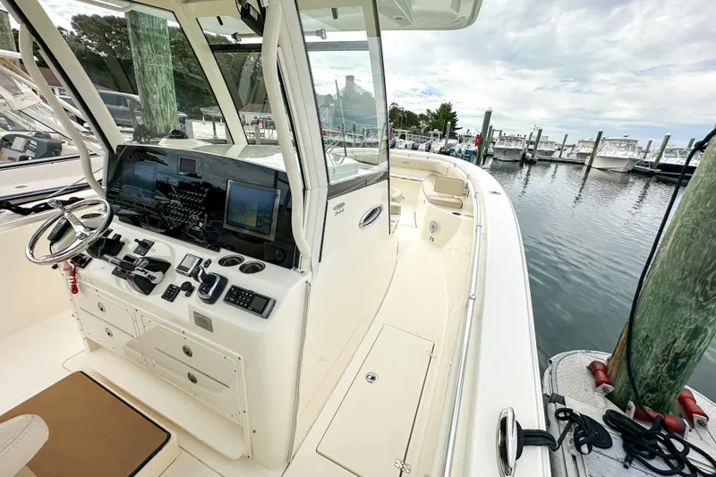 Slide: The Image of 2015 Cobia 344 Center Console boat docked, featuring a modern helm and spacious deck. - 21
