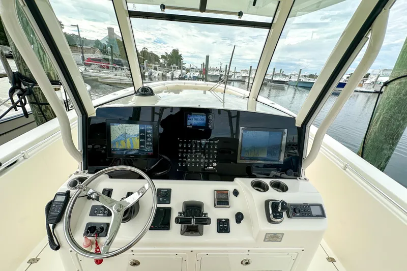 Slide: The Image of 2015 Cobia 344 Center Console helm with navigation screens and controls at marina. - 23