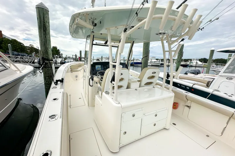 Slide: The Image of 2015 Cobia 344 Center Console boat docked at marina, featuring spacious deck and seating. - 38