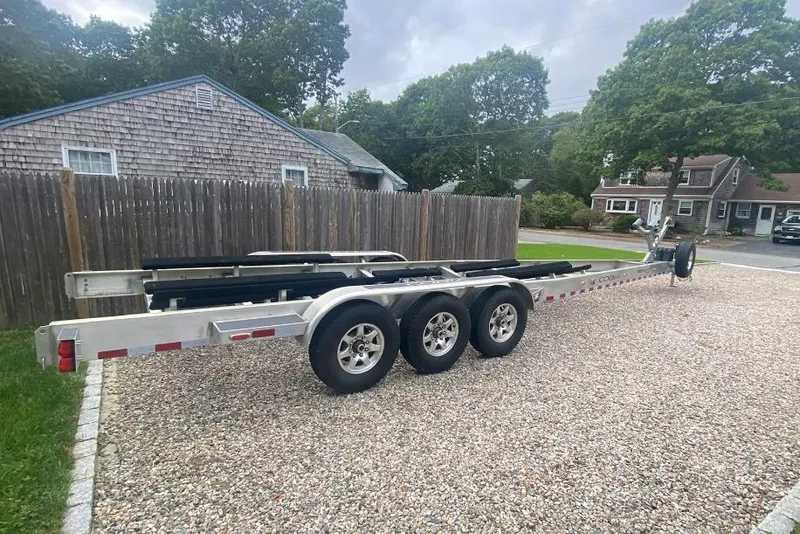 Slide: The Image of Triple-axle boat trailer for 2015 Cobia 344 Center Console, parked on gravel driveway. - 56
