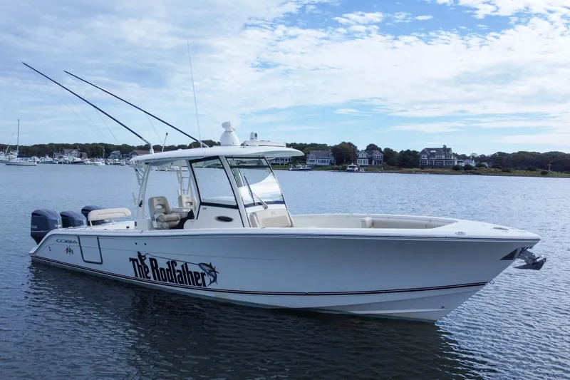 Slide: The Image of 2015 Cobia 344 Center Console boat on calm water, with fishing rods and scenic background. - 6