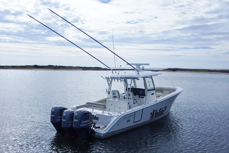 Slide: The Image of 2015 Cobia 344 Center Console boat with triple Yamaha engines on calm water. - 8