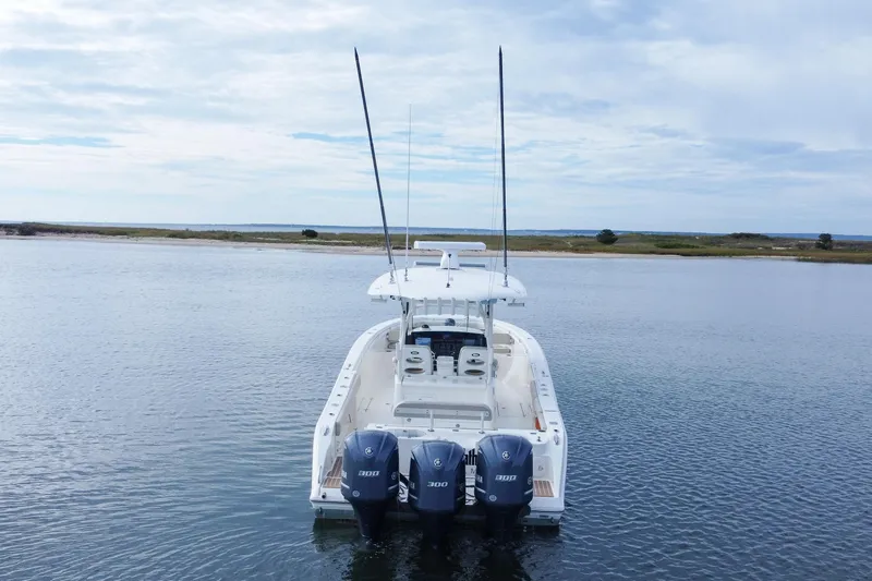 Slide: The Image of 2015 Cobia 344 Center Console boat with triple Yamaha engines on calm water. - 9