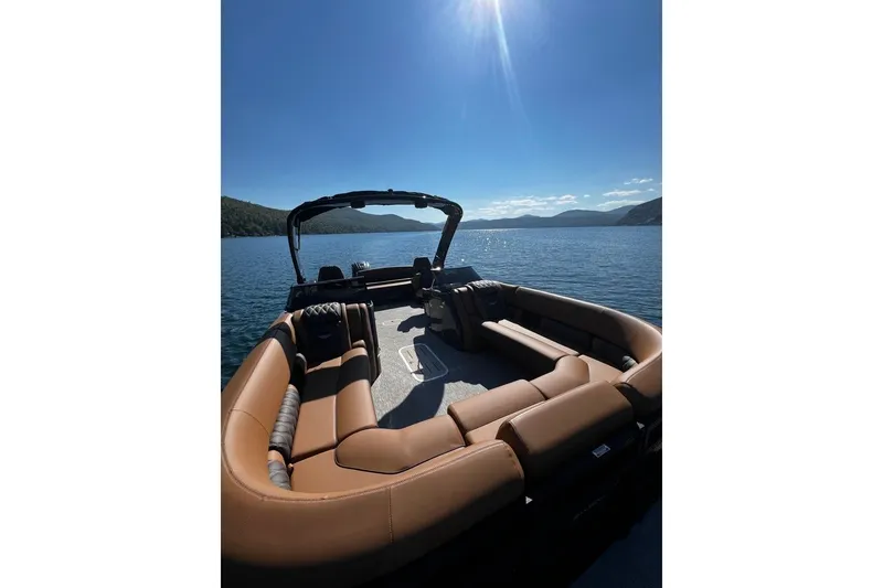 Slide: The Image of 2026 Bennington Swingback 25 pontoon boat on a serene lake under clear blue skies. - 15