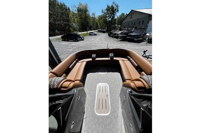 Slide: The Image of 2026 Bennington Swingback 25 boat interior with brown seating, parked outdoors. - 5