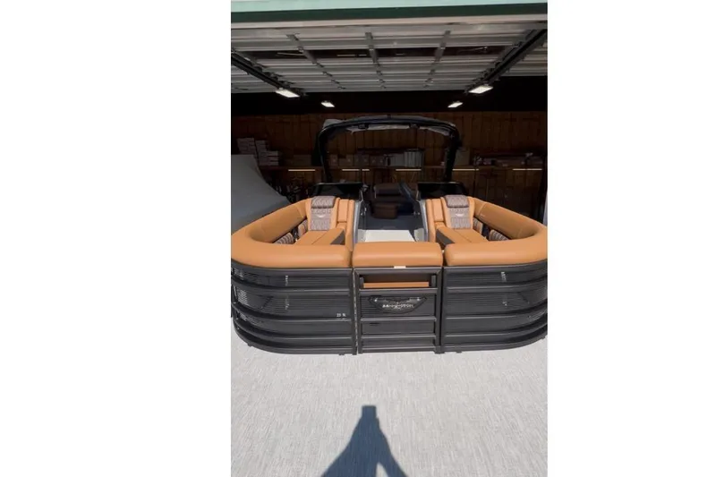 Slide: The Image of 2026 Bennington Swingback 25 pontoon boat with tan seating in a garage. - 6