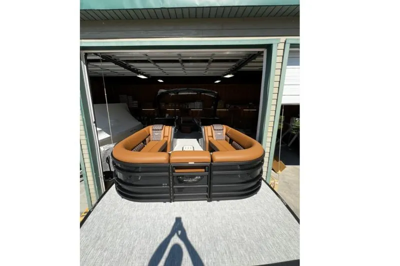 Slide: The Image of 2026 Bennington Swingback 25 pontoon boat with brown seating in a garage. - 12