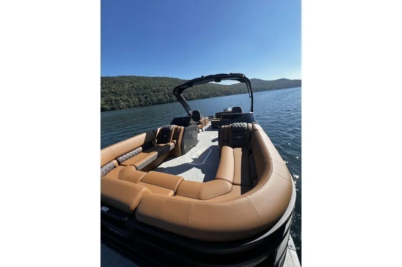 Slide: The Image of 2026 Bennington Swingback 25 pontoon boat on a serene lake with lush green hills. - 3