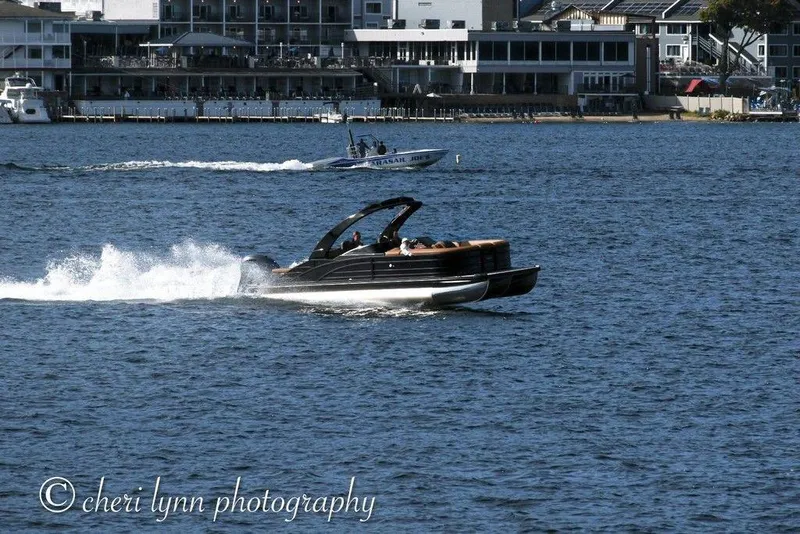 Slide: The Image of 2026 Bennington Swingback 25 cruising on a lake with waterfront buildings in the background. - 4