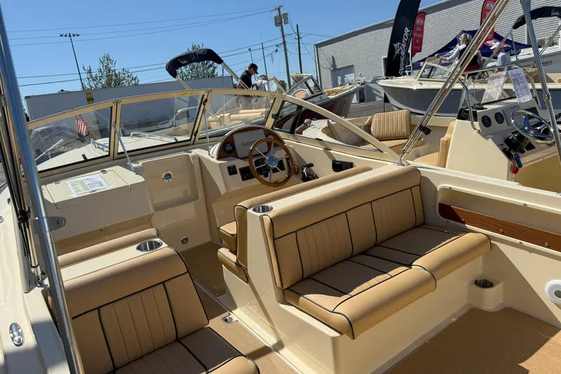 Slide: The Image of 2026 Rossiter 20 Day Boat interior with tan seating and wooden steering wheel. - 7