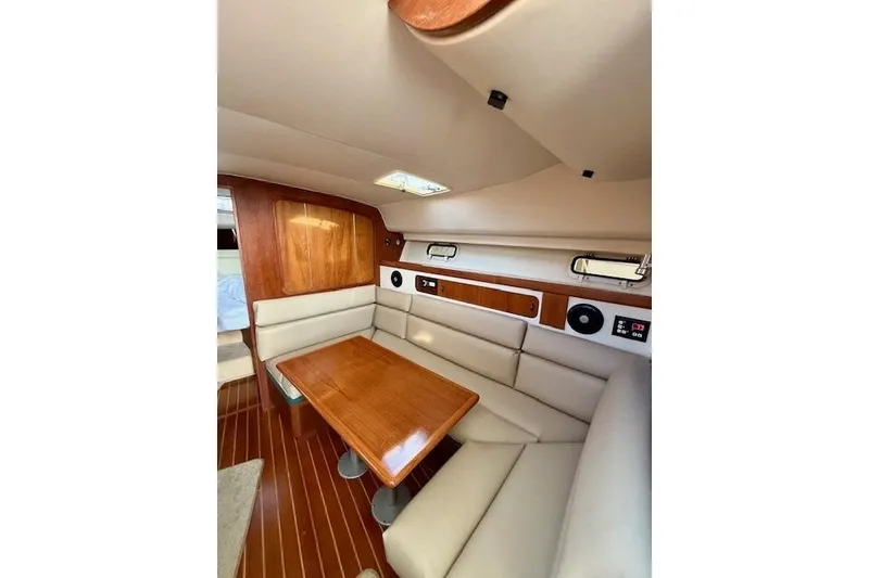 Slide: The Image of 1996 Pursuit 3100 Offshore cabin interior with wood table and cushioned seating. - 16