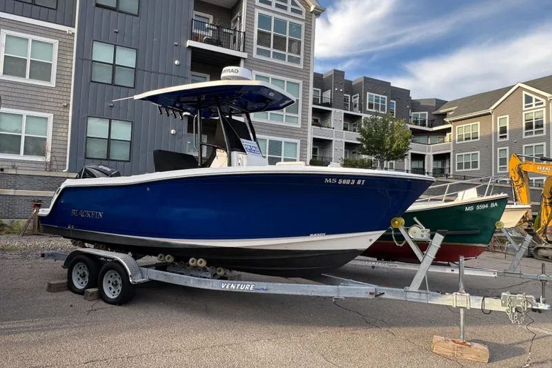 The Image of 2020 Blackfin 212 CC boat on trailer, parked near modern buildings. - 0