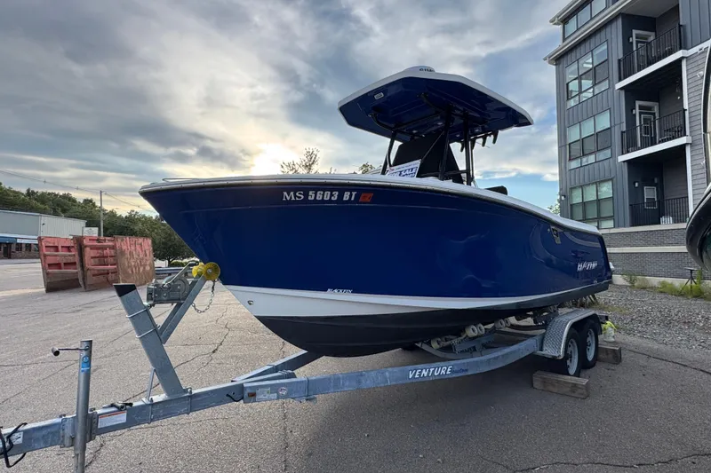 Slide: The Image of 2020 Blackfin 212 CC boat on trailer, parked near modern buildings. - 2