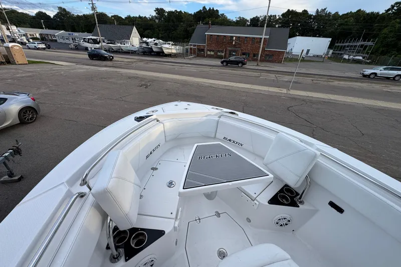 Slide: The Image of 2020 Blackfin 212 CC boat interior with seating and table, parked in a lot. - 21