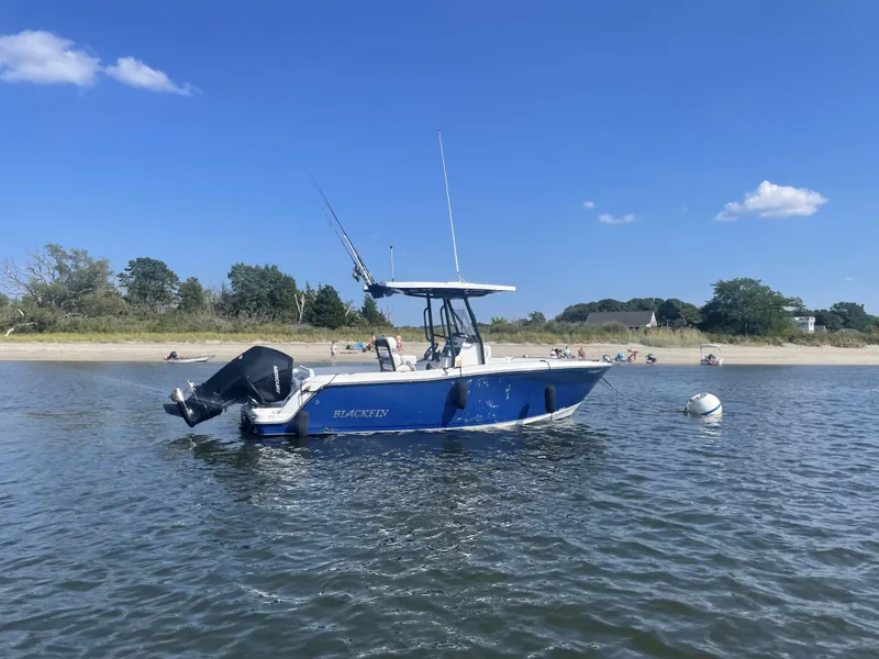 Slide: The Image of 2020 Blackfin 212 CC boat on calm water near a sandy beach under a clear blue sky. - 30
