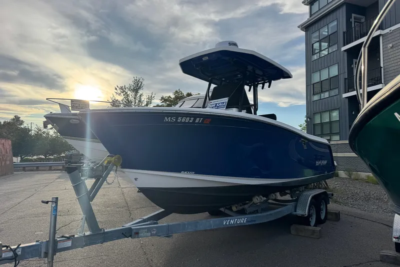 Slide: The Image of 2020 Blackfin 212 CC boat on trailer, parked near modern building at sunset. - 31