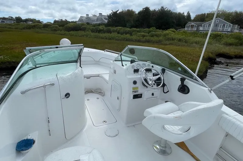 Slide: The Image of 2007 Sea Pro 216 boat interior with steering wheel and seating, docked near lush greenery. - 5