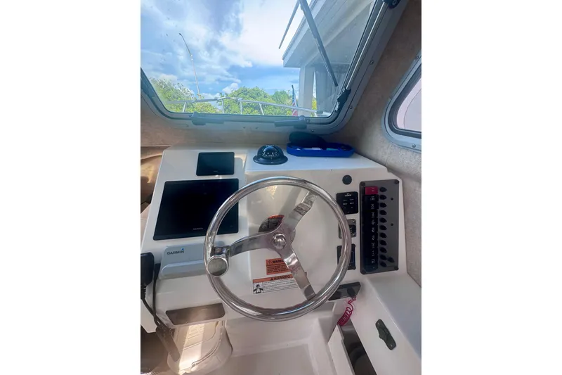 Slide: The Image of 2024 Parker 2320 Sport Cabin helm with steering wheel and navigation controls. - 18