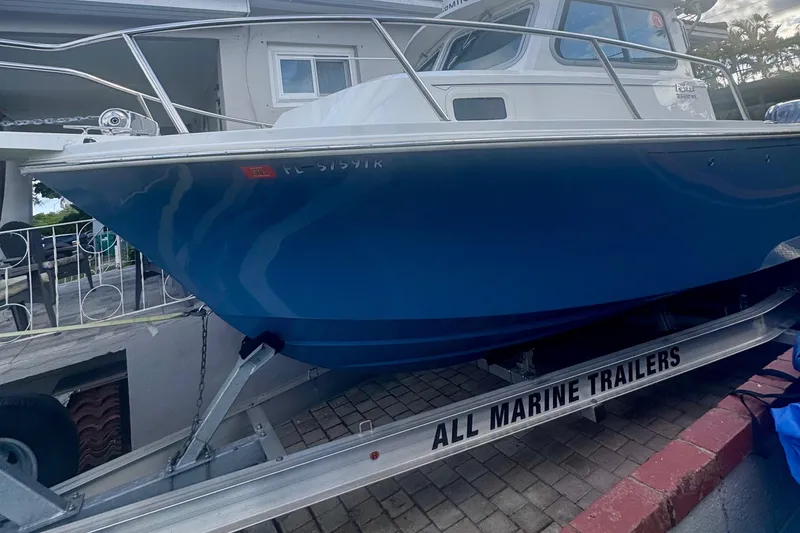 Slide: The Image of 2024 Parker 2320 Sport Cabin boat on trailer, blue hull, docked outdoors. - 3