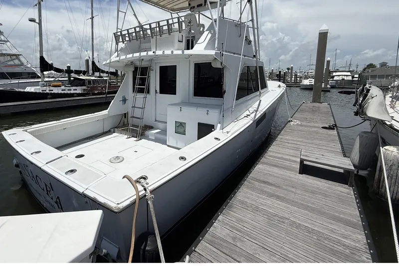Slide: The Image of 1978 Marine Management 48 Sport Fish boat docked at marina, featuring spacious deck and ladder. - 8