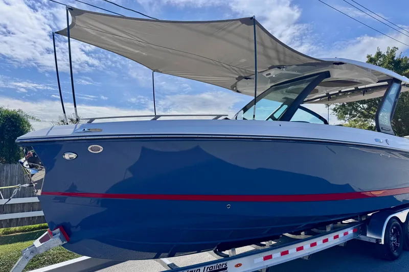 Slide: The Image of 2026 Monterey Elite 30 OB boat with canopy on trailer, under clear sky. - 23