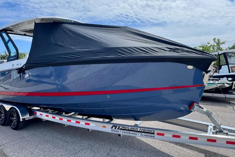 Slide: The Image of 2026 Monterey Elite 30 OB boat on trailer, covered, with blue hull and red stripe. - 25
