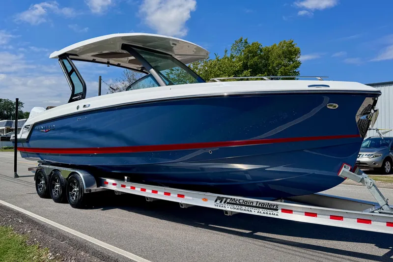 Slide: The Image of 2026 Monterey Elite 30 OB boat on a trailer, blue hull, sunny day. - 5