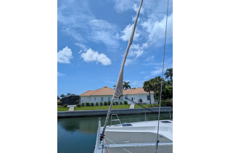 Slide: The Image of Nautitech 40 Open catamaran sailing near waterfront homes under a clear blue sky. - 28