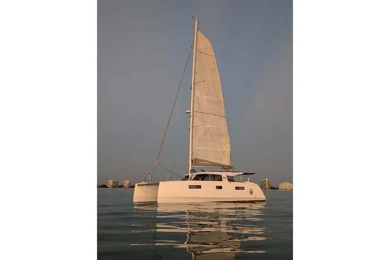 Slide: The Image of Sailing catamaran Nautitech 40 Open 2016 on calm water, city skyline in background. - 32