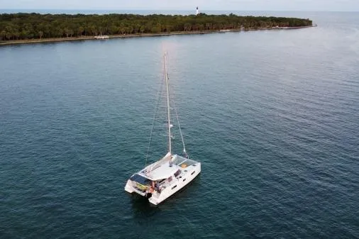 Slide: The Image of 2016 Nautitech 40 Open catamaran sailing near a lush island coastline. - 38