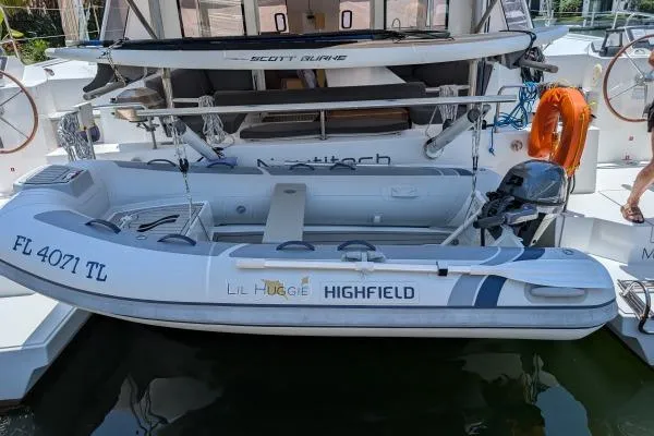 Slide: The Image of Inflatable boat attached to a 2016 Nautitech 40 Open catamaran, docked with safety equipment. - 40