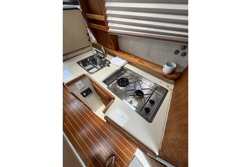 Slide: The Image of 2008 Ranger Tugs R-25 Classic galley with stove, sink, and wooden accents. - 15