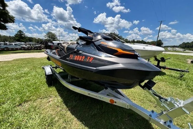 Slide: The Image of 2023 Sea-Doo GTX 170 jet ski on trailer, parked on grass under a blue sky. - 2