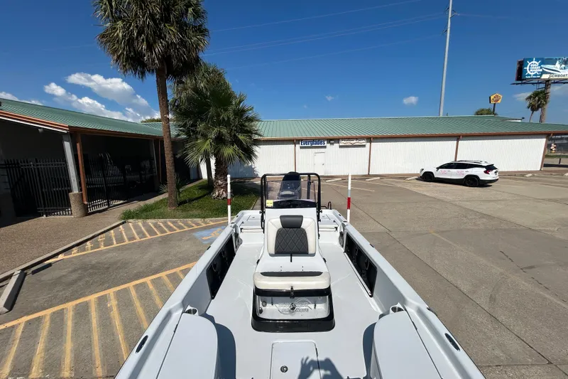 Slide: The Image of 2018 Blue Wave 2300 PureBay boat parked in sunny lot with palm trees. - 18