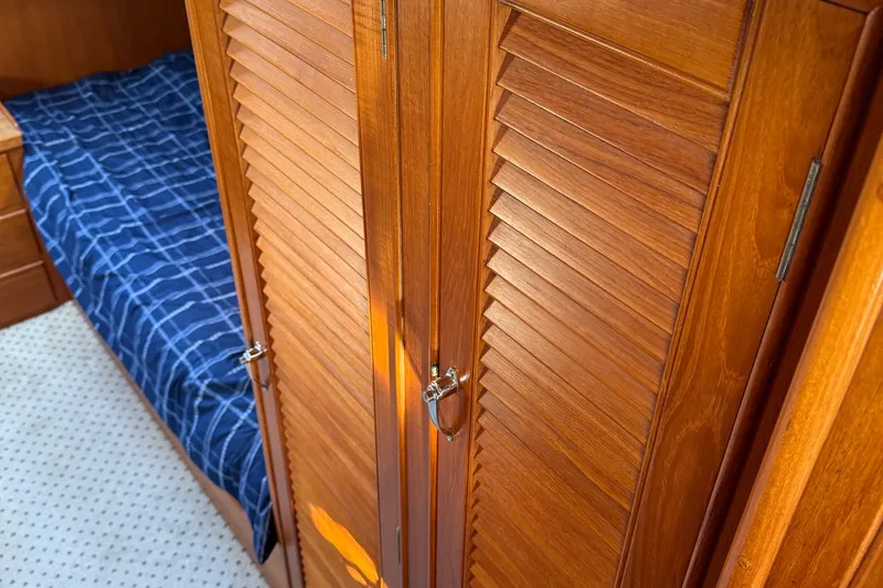 Slide: The Image of 1988 Grand Banks Heritage CL cabin with wooden closet and blue checkered bedding. - 27