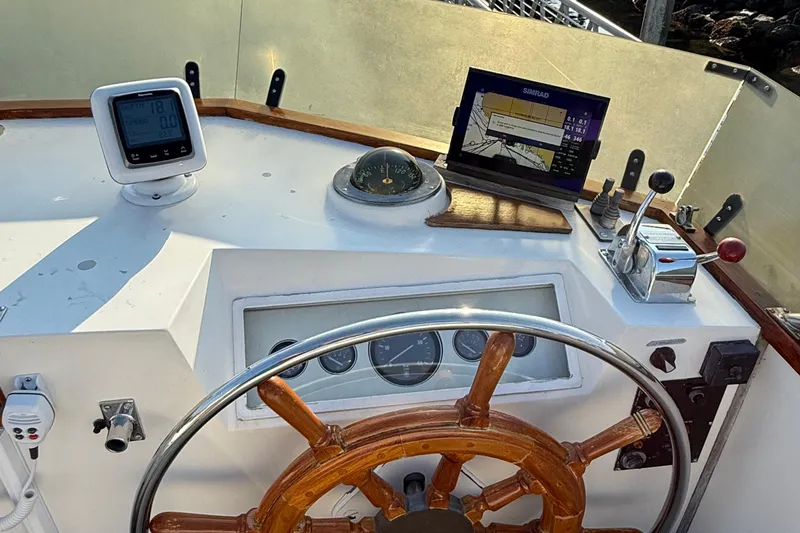 Slide: The Image of 1988 Grand Banks Heritage CL helm with wooden wheel, navigation instruments, and control panel. - 42
