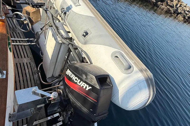 Slide: The Image of 1988 Grand Banks Heritage CL with Mercury outboard motor and inflatable dinghy on calm water. - 55