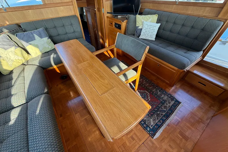 Slide: The Image of 1988 Grand Banks Heritage CL interior with wooden table, cushioned seating, and decorative pillows. - 8