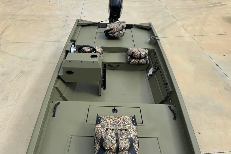 Slide: The Image of 2026 Lund 1760 Predator SC boat with camouflage seats and motor, on concrete surface. - 4