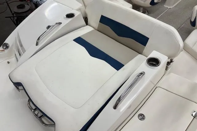 Slide: The Image of 2011 Chaparral 226 SSi boat seating with white and blue upholstery, featuring cup holders and handles. - 12