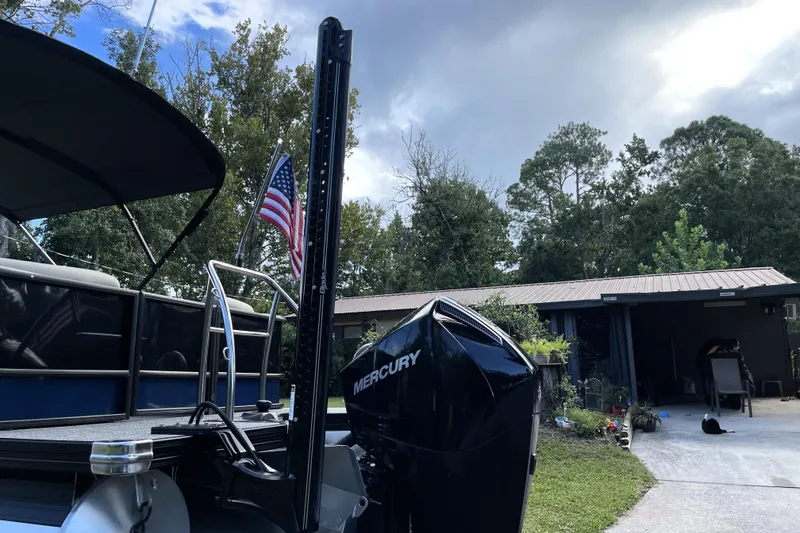 Slide: The Image of 2022 Barletta Cabrio 22QC pontoon boat with Mercury engine, parked near a garage. - 14