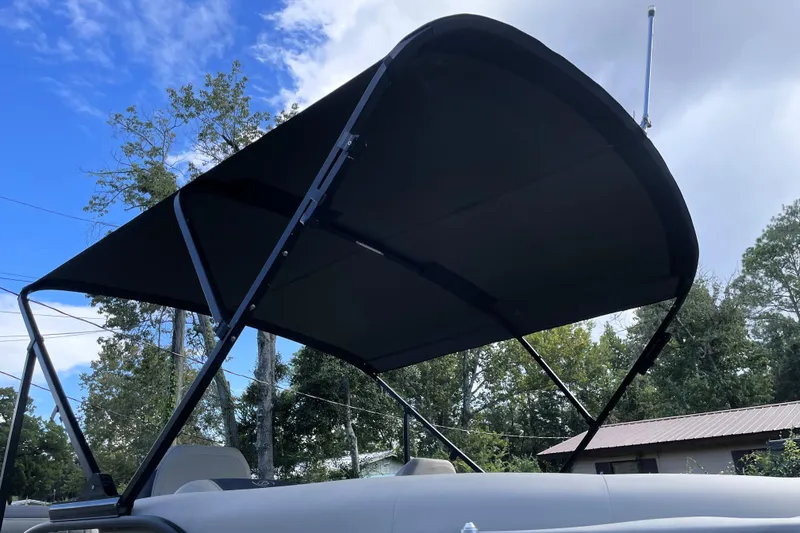 Slide: The Image of 2022 Barletta Cabrio 22QC boat with canopy against a blue sky and trees. - 18