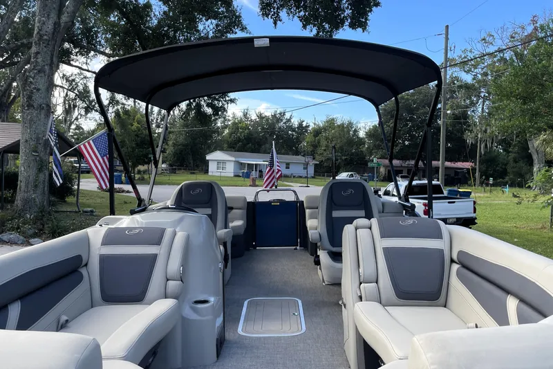 Slide: The Image of 2022 Barletta Cabrio 22QC pontoon boat with spacious seating and canopy in a residential area. - 22
