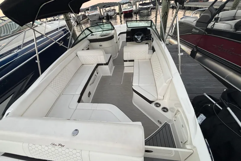 Slide: The Image of 2019 Sea Ray SDX 270 boat interior with white seating and sleek design at a marina. - 19
